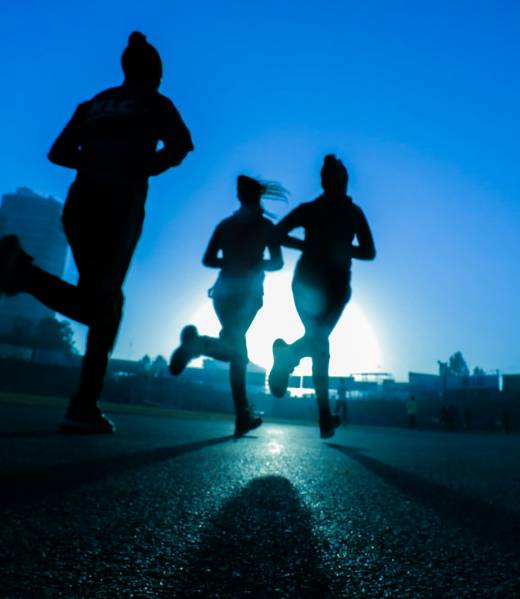 silhouette of three women running on grey concrete road